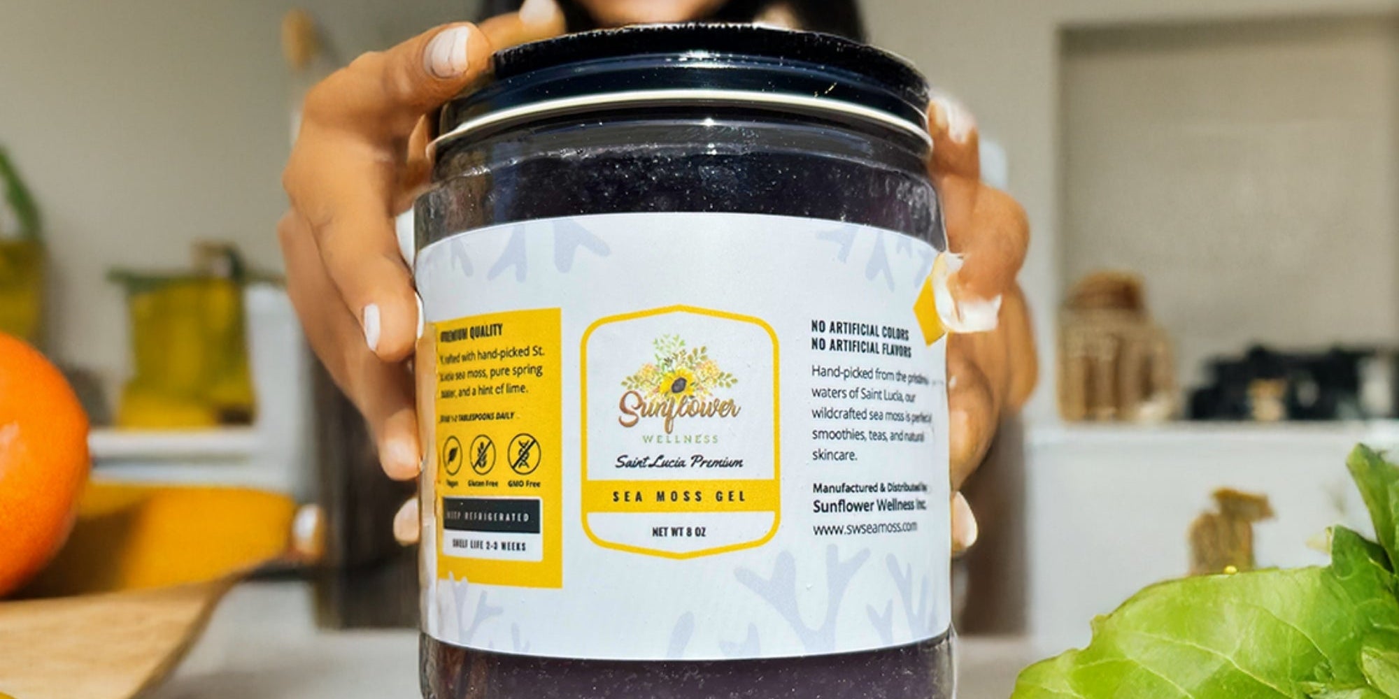 Smiling woman holding a jar of Sunflower Wellness Full Spectrum Sea Moss Gel, showcasing its rich natural color and premium quality.